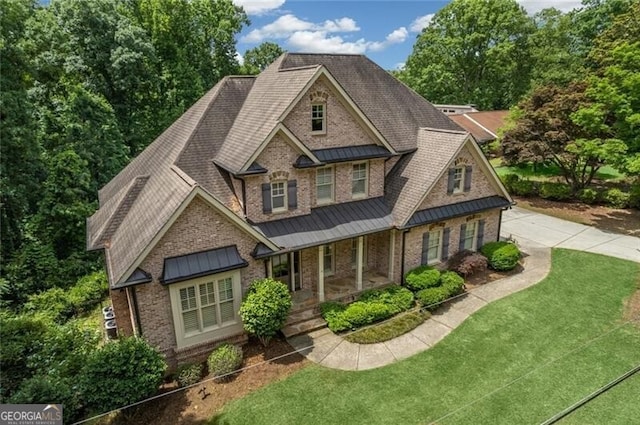 craftsman-style house with a front yard, a standing seam roof, a porch, brick siding, and metal roof