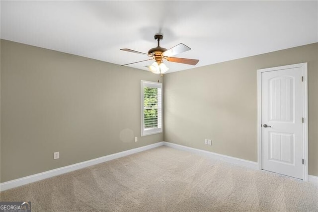 spare room with light colored carpet, baseboards, and ceiling fan