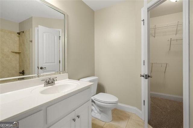 bathroom with tile patterned floors, toilet, vanity, walk in shower, and a spacious closet