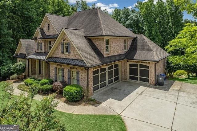 view of front of house featuring brick siding, concrete driveway, metal roof, an attached garage, and a standing seam roof