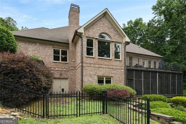 exterior space featuring brick siding, fence, a chimney, a yard, and a sunroom