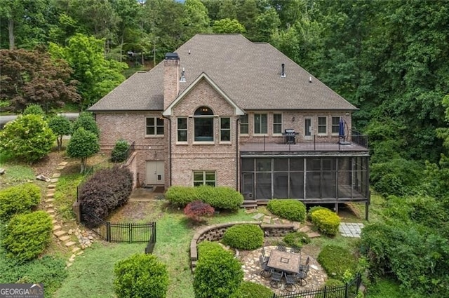 rear view of house with a chimney, fence, a yard, and a sunroom