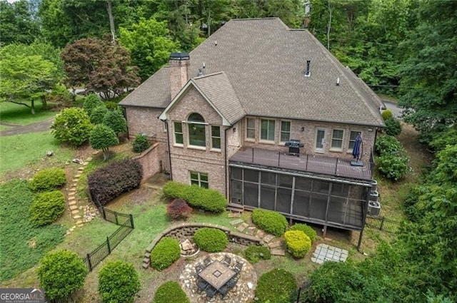 back of house featuring fence, a yard, roof with shingles, a sunroom, and a chimney