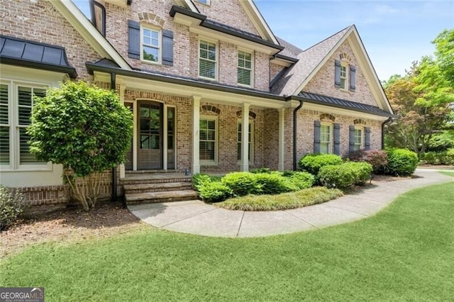 view of front of house featuring brick siding, a front lawn, a standing seam roof, and metal roof