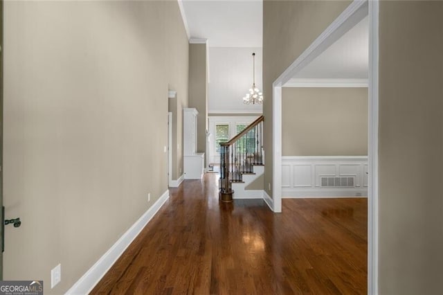 foyer entrance with visible vents, a notable chandelier, ornamental molding, wood finished floors, and stairway