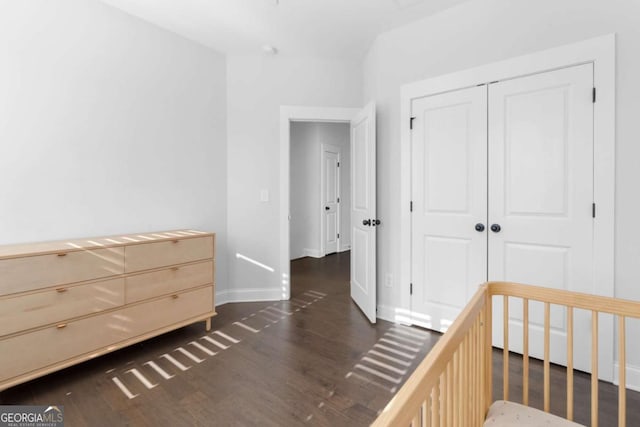 unfurnished bedroom featuring dark wood-style floors, baseboards, and a closet