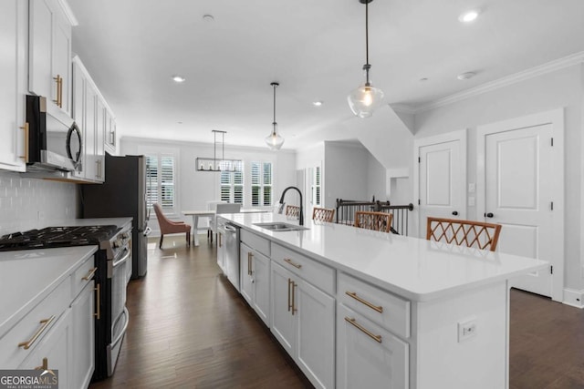 kitchen featuring ornamental molding, a center island with sink, a sink, dark wood-style floors, and stainless steel appliances