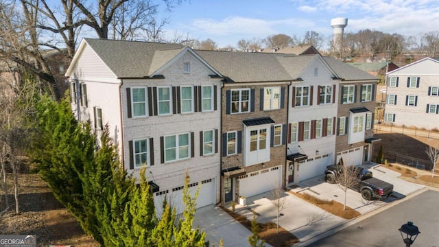 townhome / multi-family property featuring a garage, a residential view, and driveway