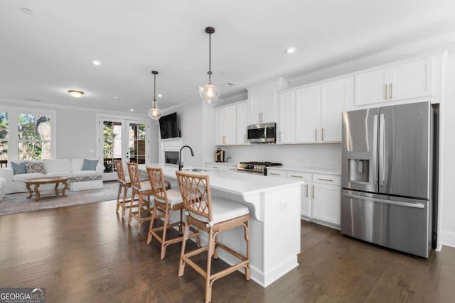 kitchen featuring open floor plan, an island with sink, light countertops, appliances with stainless steel finishes, and dark wood-style floors