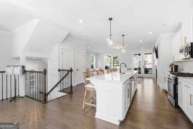 kitchen with a kitchen bar, a sink, french doors, appliances with stainless steel finishes, and white cabinets