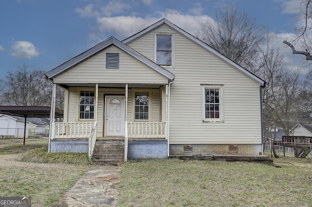 bungalow featuring fence, covered porch, a front yard, crawl space, and a carport