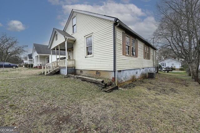 view of side of property featuring cooling unit, a yard, and crawl space