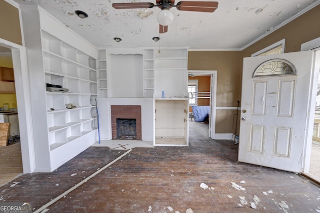 unfurnished living room with crown molding, built in features, a fireplace, wood finished floors, and a ceiling fan