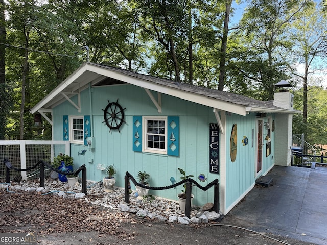 view of front of house with roof with shingles, fence, and a chimney