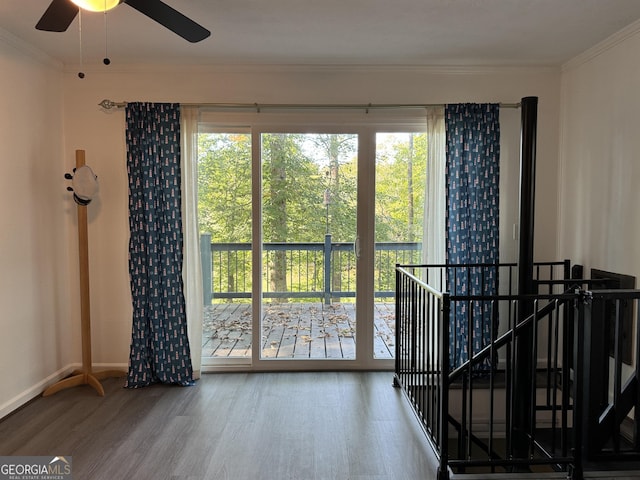 interior space with baseboards, wood finished floors, ceiling fan, and ornamental molding