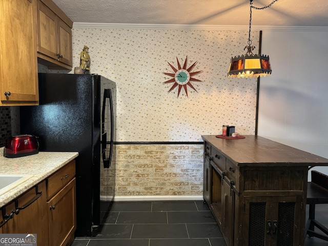 kitchen with dark tile patterned floors, a textured ceiling, freestanding refrigerator, and ornamental molding