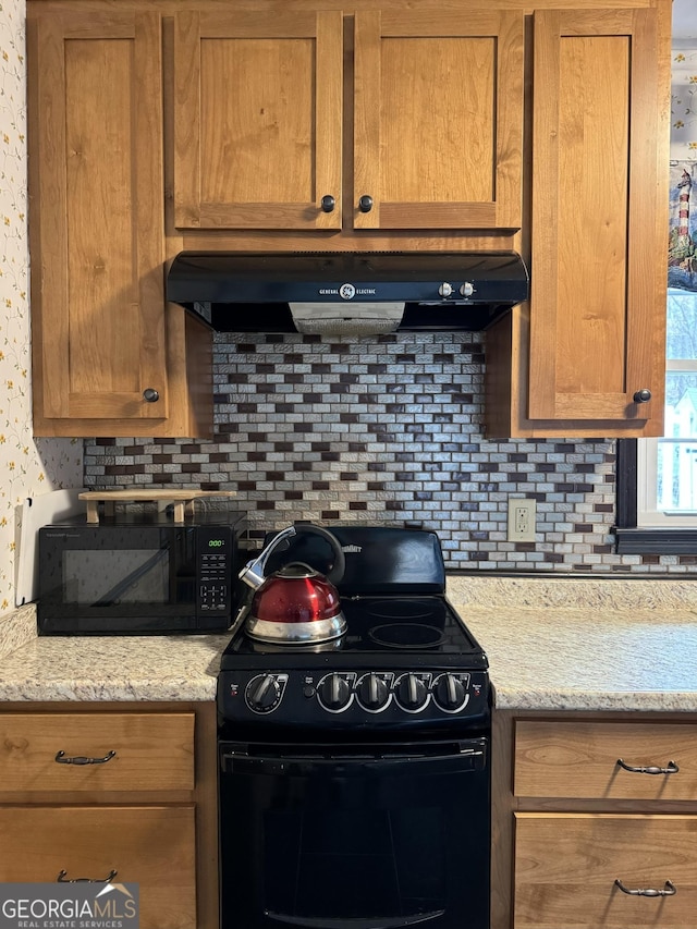 kitchen featuring black appliances, backsplash, brown cabinetry, and under cabinet range hood