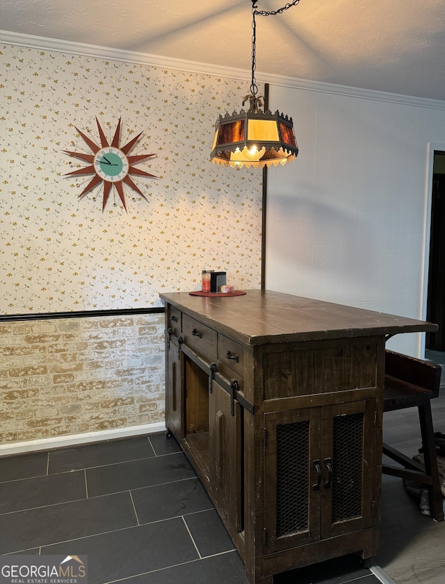 bar featuring hanging light fixtures, baseboards, dark tile patterned floors, and ornamental molding