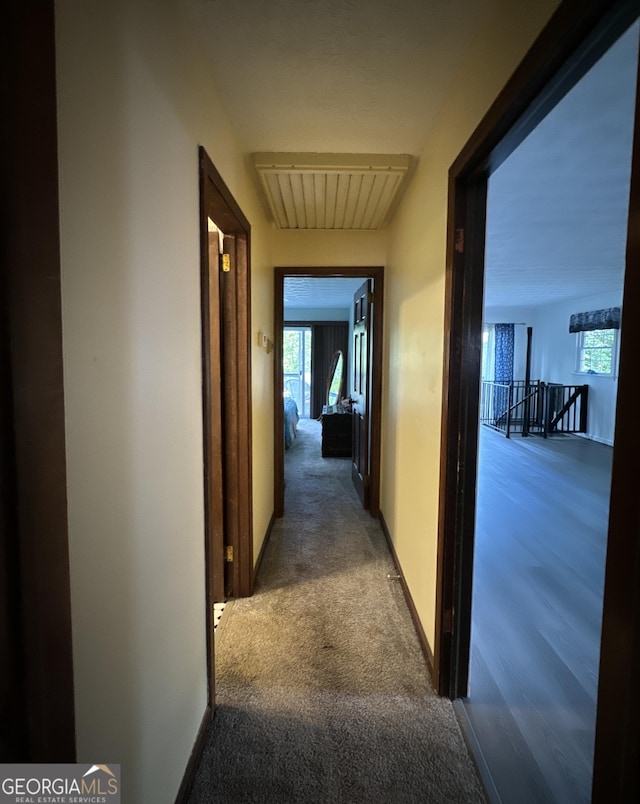 corridor with an upstairs landing, visible vents, and carpet floors