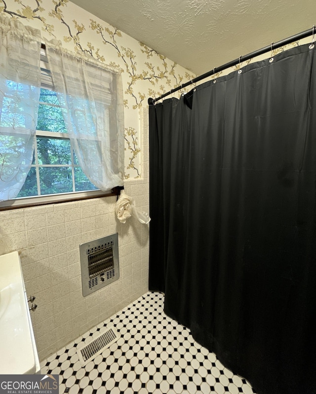 full bath with visible vents, heating unit, a textured ceiling, a shower with shower curtain, and wallpapered walls