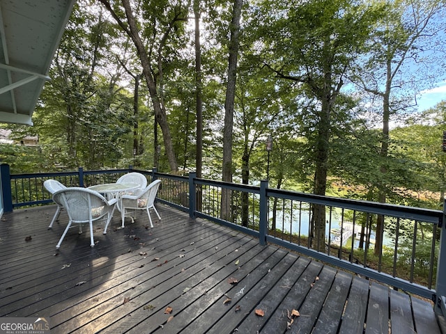 deck with a water view and outdoor dining space