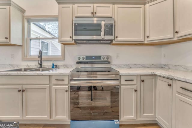 kitchen featuring light stone counters, appliances with stainless steel finishes, and a sink