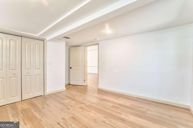 below grade area with visible vents, baseboards, and light wood-style floors