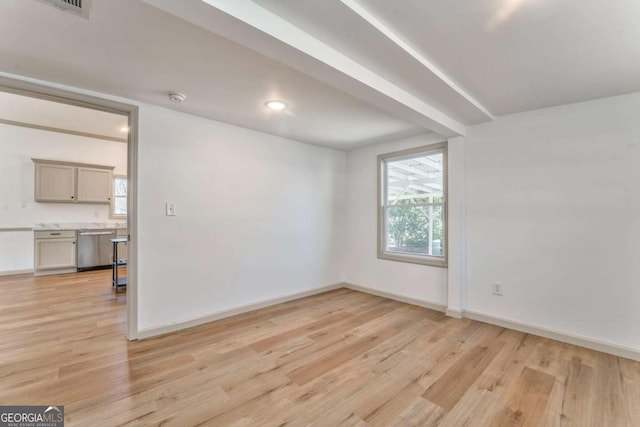 empty room featuring light wood finished floors, baseboards, and a wealth of natural light