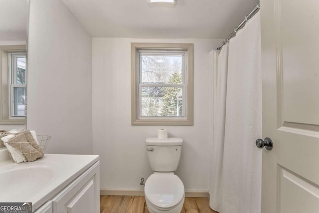 bathroom featuring toilet, a healthy amount of sunlight, wood finished floors, and vanity