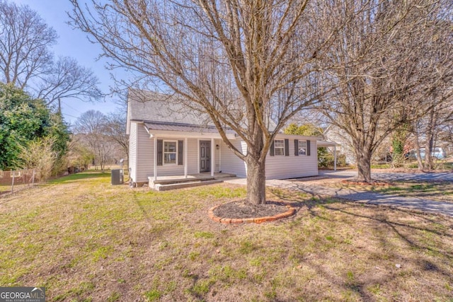 view of front of property with covered porch, central AC, a front yard, and fence