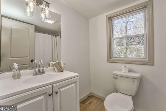 bathroom with toilet, vanity, baseboards, and wood finished floors