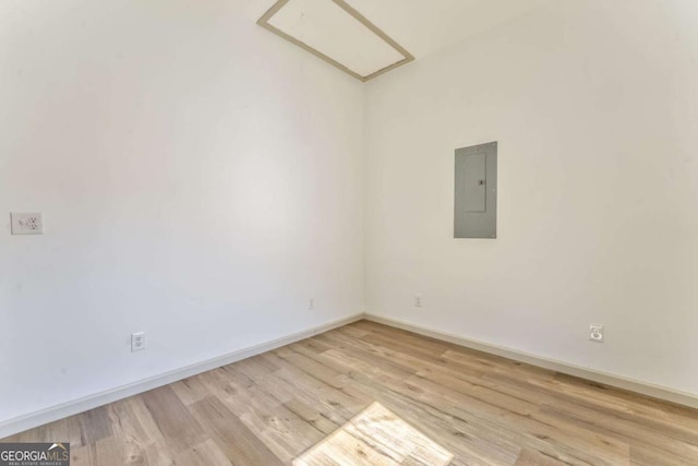 unfurnished room with electric panel, light wood-style flooring, and baseboards