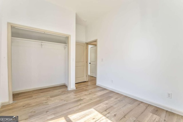 unfurnished bedroom with a closet, baseboards, and light wood-style floors