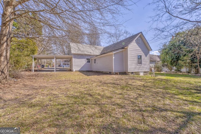 rear view of house featuring a carport and a yard