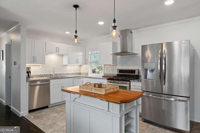 kitchen featuring butcher block countertops, a sink, stainless steel appliances, wall chimney exhaust hood, and crown molding