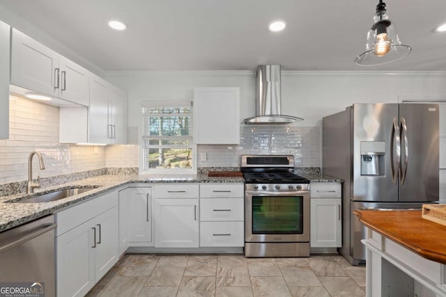 kitchen with a sink, ornamental molding, stainless steel appliances, white cabinetry, and wall chimney exhaust hood