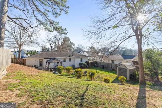 back of property with an outbuilding, a yard, a fenced backyard, a gazebo, and a storage unit