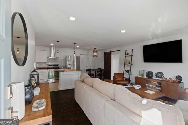 living room featuring recessed lighting, a barn door, dark wood-style floors, and ornamental molding