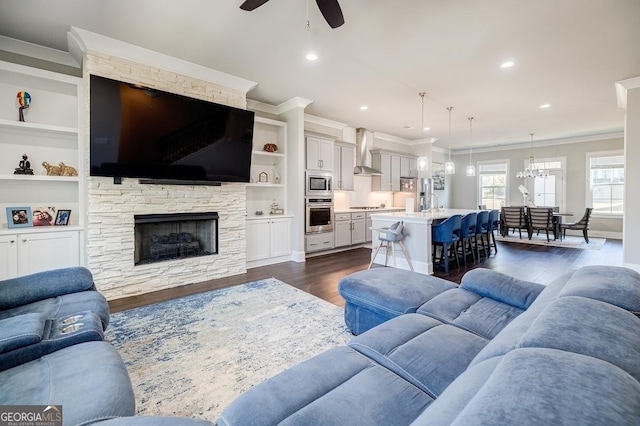 living room featuring built in shelves, ornamental molding, recessed lighting, a fireplace, and dark wood-style flooring