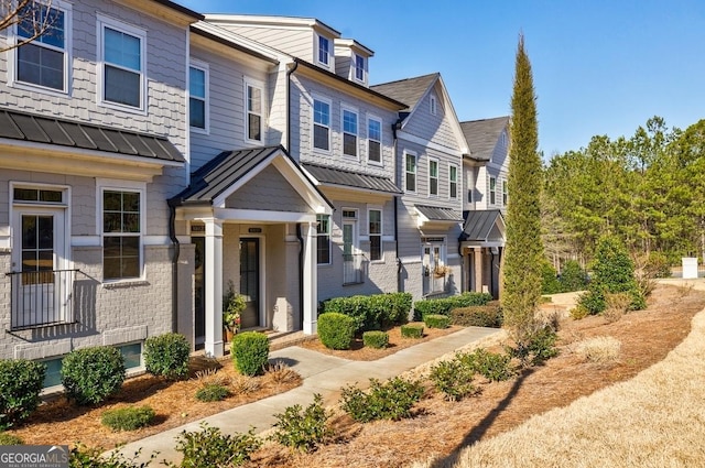 townhome / multi-family property with a standing seam roof, brick siding, and metal roof