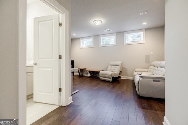 living area with a wealth of natural light, visible vents, baseboards, and dark wood finished floors