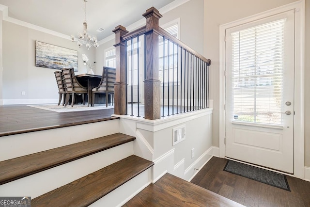 foyer entrance with stairway, baseboards, an inviting chandelier, dark wood-style flooring, and crown molding