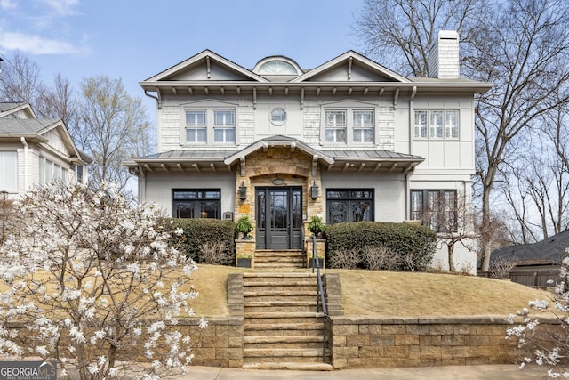 view of front facade featuring metal roof, brick siding, a chimney, and a standing seam roof