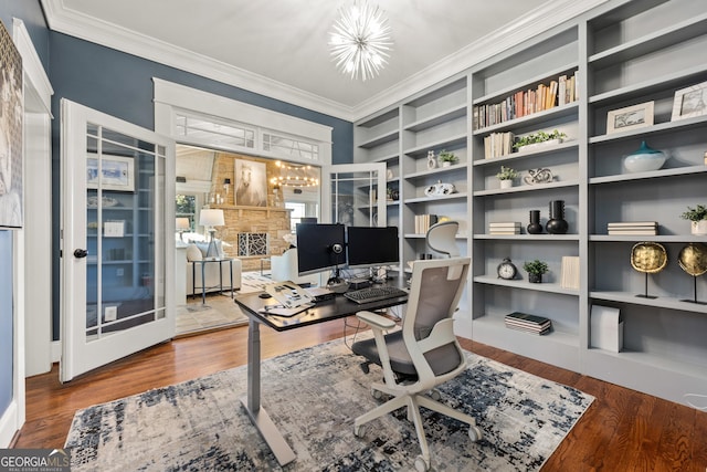 office area featuring built in shelves, ornamental molding, wood finished floors, a fireplace, and a chandelier