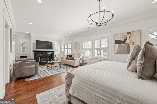 bedroom with a fireplace, wood finished floors, visible vents, and ornamental molding