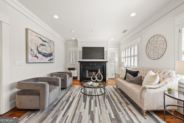 living room featuring visible vents, ornamental molding, a glass covered fireplace, wood finished floors, and recessed lighting