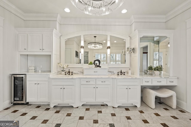 full bath featuring beverage cooler, baseboards, double vanity, crown molding, and a notable chandelier