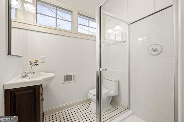 bathroom with visible vents, toilet, a tile shower, baseboards, and vanity