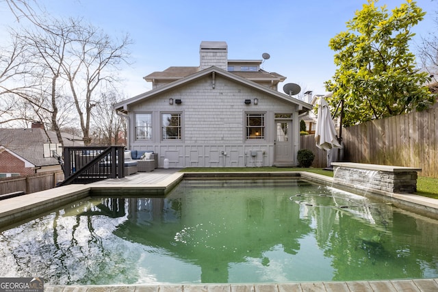 rear view of house featuring a deck, a chimney, and a fenced backyard