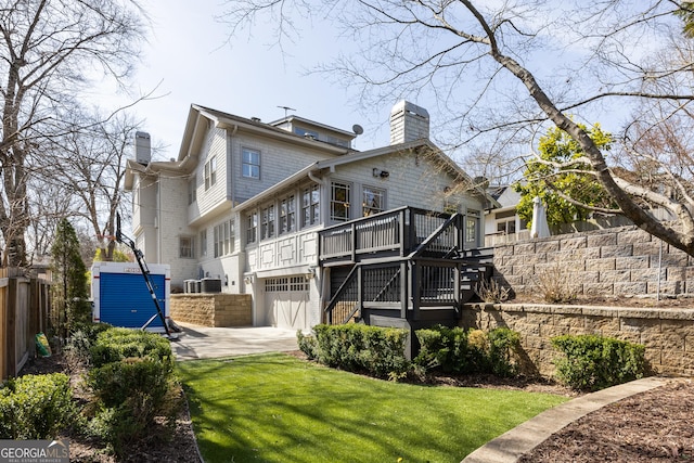 rear view of house with stairway, an attached garage, a chimney, and fence